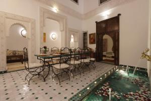 ein Esszimmer mit einem Tisch, Stühlen und einem Pool in der Unterkunft Riad Jenan L'mouassine in Marrakesch