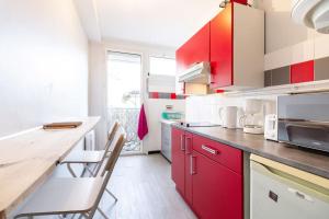 una cocina con armarios rojos y una barra con sillas en La chambre des secrets / parking / wifi, en Toulouse