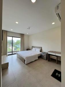 Căn hộ Aria Resort Vũng Tàu 3 Phòng ngủ في Xã Thắng Nhứt: غرفة نوم بها سرير وطاولة ونافذة