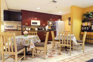 a kitchen with a table and chairs and a refrigerator at Hometown Inn & Suites Jacksonville Butler Blvd./Southpoint in Jacksonville