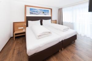 ein Schlafzimmer mit einem großen Bett mit weißer Bettwäsche in der Unterkunft Stöcklhof in Pettneu am Arlberg
