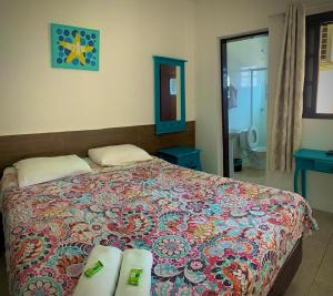 um quarto com uma cama com uma colcha colorida em Pousada Acqua Infinity em Bertioga