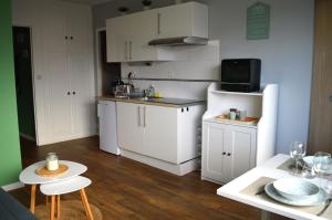 uma cozinha com armários brancos e um frigorífico branco em Le Cocon de Nacre - à 300m de la plage - wifi em Courseulles-sur-Mer