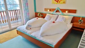 Schlafzimmer mit einem Bett mit weißer Bettwäsche und Kissen in der Unterkunft Motel Brunner Apartments & Zimmer in Bad Eisenkappel