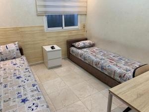 a room with two beds and a table and a window at Petite Villa de 160m2 à Mohammedia in Mohammedia