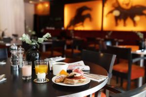 a table with a plate of food and orange juice at ProfilHotels Aveny in Umeå