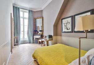a bedroom with a yellow bed and a desk at Appartement de standing sur l'île Saint-Louis by Weekome in Paris