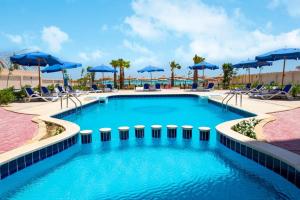 洪加達的住宿－Casablanca beach resort, first line, with private beach and swimming pools,hurghada，一个带蓝伞和椅子的大型游泳池