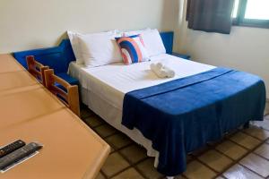 ein Bett mit einer blauen Decke und zwei ausgestopften Tieren darauf in der Unterkunft Pousada Casa Grande in Bonito