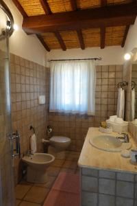 ein Bad mit einem Waschbecken, einem WC und einem Fenster in der Unterkunft Stazzu Barecca B&B in Cugnana Verde