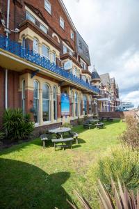 un edificio con mesas de picnic delante de él en Palm Court Hotel, en Great Yarmouth