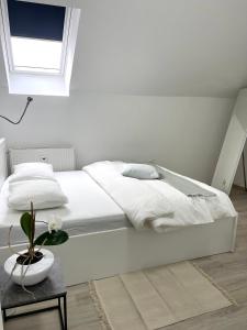 a white bedroom with a white bed and a table at The City Loft in Ljubljana