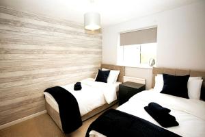 a bedroom with two beds and a wooden wall at Wigmore Lodge - FREE Parking & Airport & M1 & Contractor & Leisure in Luton