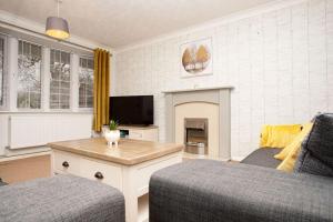 ein Wohnzimmer mit einem Sofa und einem TV in der Unterkunft Wigmore Lodge - FREE Parking & Airport & M1 & Contractor & Leisure in Luton