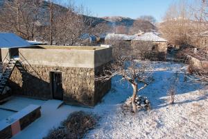 un viejo edificio de piedra en la nieve con un árbol en Zove Rural Cottage with garden views, en Kʼarashamb