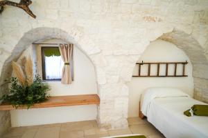 ein Schlafzimmer mit einer Steinmauer, einem Bett und einem Fenster in der Unterkunft Antiche Dimore TerraRossa in Alberobello