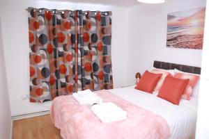 1 dormitorio con cama con almohadas rojas y cortina en Lovely 2-Bed Apartment in Harrow en Harrow