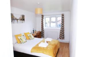 Un dormitorio con una cama con almohadas amarillas y una ventana en Lovely 2-Bed Apartment in Harrow en Harrow