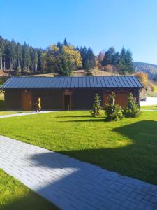 a large barn with a person walking in the grass at Apartmány u Ivanky, Polanský dvůr 1149 in Velké Karlovice