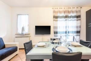 a dining room with a table with chairs and a tv at Limone Apartment - Featuring a Private Garden and Access to a Pool in Barcuzzi