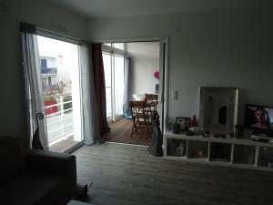 a living room with a door open to a balcony at Le Neptune in Contis-les-Bains