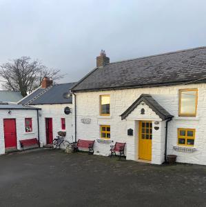 un edificio blanco con puertas rojas y amarillas en Nellie's Farmhouse en Carlingford