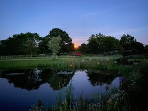 Vragender的住宿－Achterhoeks Goed, Minicamping in Vragender，公园里的池塘,背面是日落