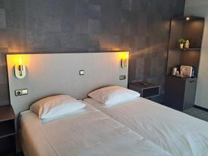 een slaapkamer met een wit bed met 2 kussens bij Parkhotel Horst - Venlo in Horst