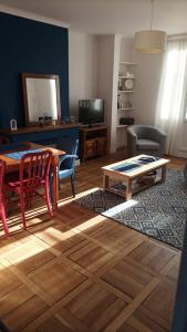 uma sala de estar com uma mesa e cadeiras e uma televisão em Le Bleu Roi - Appartement calme proche de la Gare em Caen