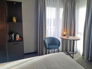 ein Schlafzimmer mit einem Bett, einem Tisch und einem blauen Stuhl in der Unterkunft Parkhotel Horst - Venlo in Horst