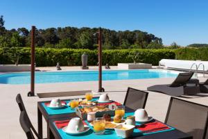 a table with food on it next to a pool at Hôtel La Bastide Saint Martin in Carcassonne