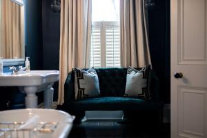 a bathroom with a green chair and a sink at No38 The Park in Cheltenham