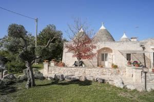 a stone house with a stone wall and a yard at Antiche Dimore TerraRossa in Alberobello