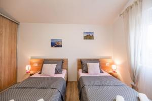 dwa łóżka w małym pokoju z dwoma lampami w obiekcie Holiday Home Aria w Nin