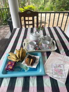 a table with a tray of food and a tea set at Rose Dale Homestay Ella in Ella