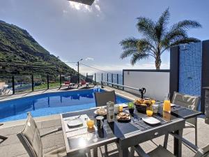 a table with food on it next to a swimming pool at Villa Stella by LovelyStay in Arco da Calheta