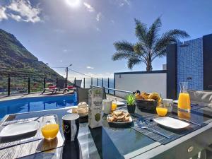 a table with food on top of a balcony with a pool at Villa Stella by LovelyStay in Arco da Calheta