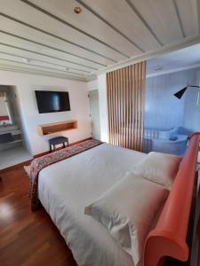 1 dormitorio con 1 cama grande y TV en Pátio da Figueira, en Torres Vedras