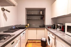 L'Appartement du "Coup de Coeur de Sarlat" في سارلا لا كانيدا: مطبخ مع خزائن بيضاء وغسالة ومجفف