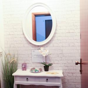 un espejo en una pared sobre una mesa blanca con una flor en Guest House Benny, en Reggio Emilia