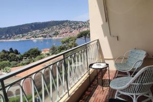 uma varanda com 2 cadeiras e vista para a água em Bel appartement climatisé vue mer parking gratuit. em Villefranche-sur-Mer