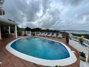 a swimming pool on a patio with chairs and the ocean at Stunning 4-Bed Villa in Gros Islet St Lucia in Bois dʼOrange