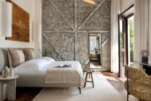 Pereh Mountain Resort في Gadot: غرفة نوم بسرير وجدار حجري