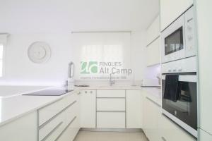 a kitchen with white cabinets and a sign that reads campuses art camp at piso alto standing en Segur de Calafell in Calafell