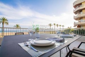 a table with plates and glasses on a balcony with the beach at piso alto standing en Segur de Calafell in Calafell