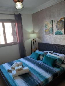 - une chambre avec un lit bleu et des serviettes dans l'établissement Lilacs Garden Cabo Negro Piscines WiFi -only family, à Cabo Negro