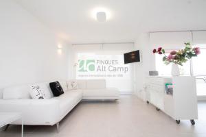 a white living room with a white couch and a tv at piso alto standing en Segur de Calafell in Calafell