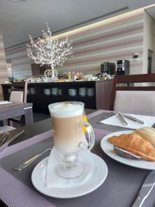 a cup of coffee and a plate of bread on a table at Hotel Monte Lírio in Espinho