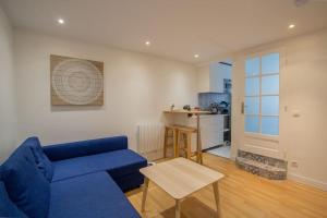 sala de estar con sofá azul y cocina en Au petit gnolles - 450m Métro - 100m Parc en París