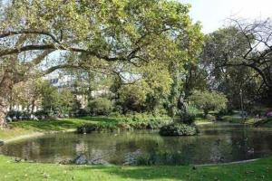 un estanque en un parque con árboles y césped en Au petit gnolles - 450m Métro - 100m Parc en París